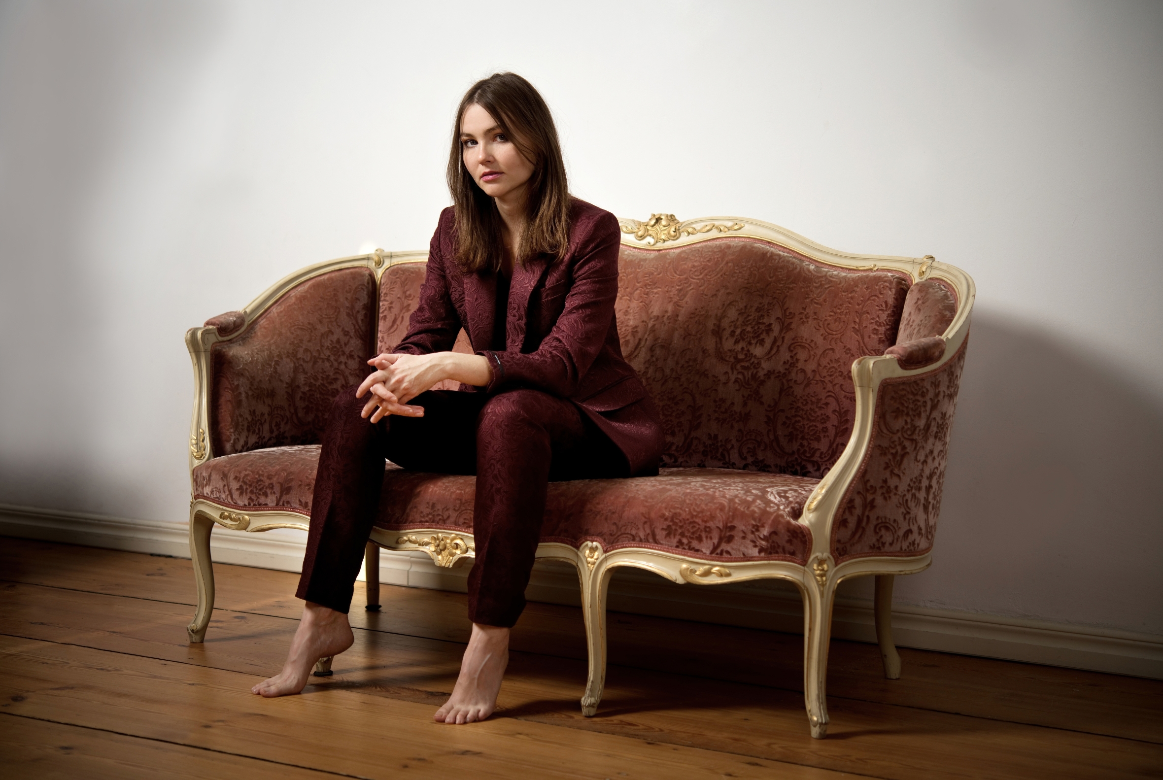 Mareike Plota-Neumann im bordeauxroten Anzug auf einem historischen Sofa
